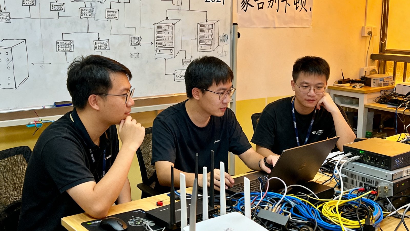 2021年竞技宝创业初期，三位创始人在深圳大学城共享工位工作的场景，桌上堆满了网络设备和测试用的路由器，白板上画满了服务器架构草图，墙上贴着'让每个玩家告别卡顿'的手写标语